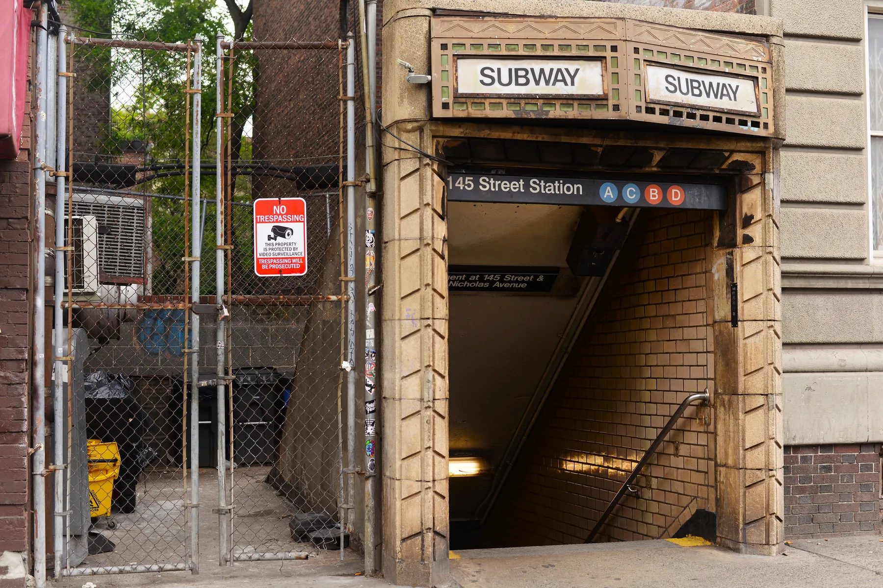 A stone subway entrance marked 145 Street Station, with the A, C, B and D lines shown on its sign